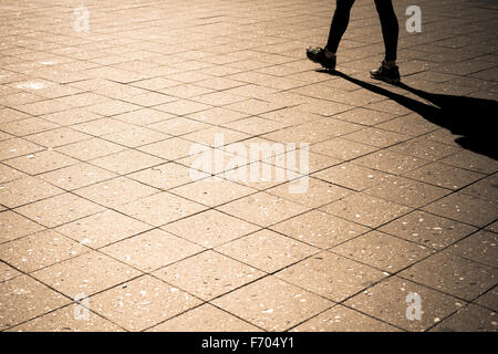 Minimalist image of person and shadow walking outdoors. Stock Photo