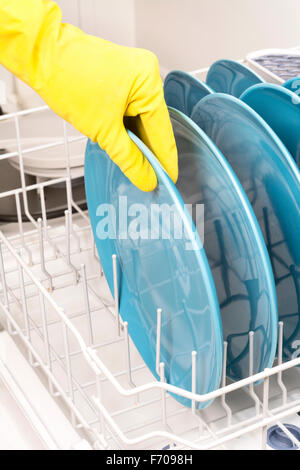 A woman removes dishes after they are finished being washed in a dishwasher Stock Photo