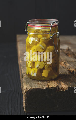 Feta cheese marinated with herbs and spices in olive oil in a glass jar Stock Photo
