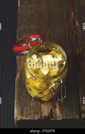 Feta cheese marinated with herbs and spices in olive oil in a glass jar Stock Photo