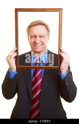 Smiling senior businessman looking through an empty picture frame Stock Photo