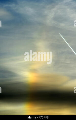 Aberystwyth, UK. 23rd November, 2015. UK Weather: A sundog, or parhelion, appears in the sky over west Wales. This phenomenon is due to the light of the sun being refracted through ice in the upper atmosphere. A jet trail from an aircraft gives an idea of scale. John Gilbey/Alamy Live News Stock Photo