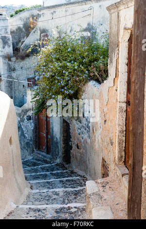 Santorini, Thira. Rural village of Exo Gonia. Long stone steps leading down a narrow lane between rustic houses. Stone and plaster walls with doors.