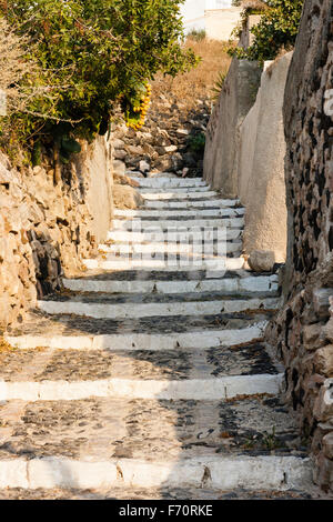 Santorini, Thira. Rural village of Exo Gonia. Long stone steps leading up a narrow lane between rugged stone and plaster walls. Daytime.