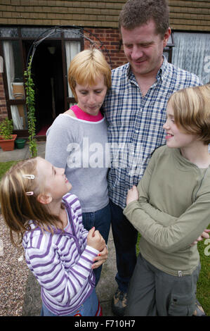 Family smiling together outside house Stock Photo - Alamy