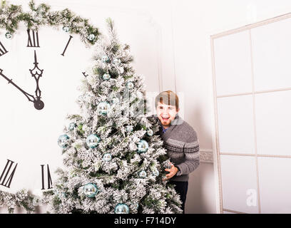 young man standing behind a Christmas tree Stock Photo