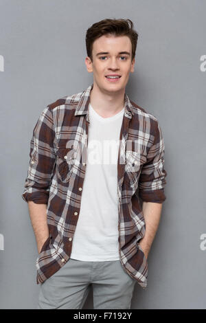 Portrait of handsome young happy positive man in checkered shirt  posing and smiling on gray background Stock Photo