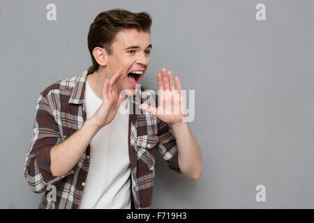 Portrait of handsome young  screaming man in plaid shirt isolated on gray background Stock Photo