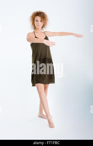 Full length portrait of a young woman in dress and curly hair dancing isolated on a white background Stock Photo