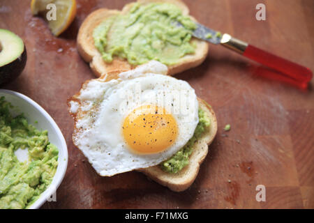 Two slices of avocado toast, one with a fried egg on top Stock Photo