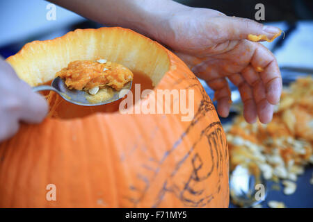 Scooping out seeds and other material from a pumpkin before carving Stock Photo