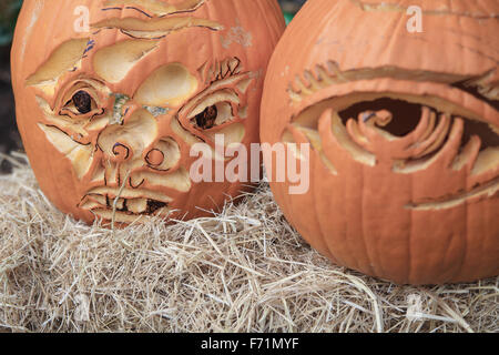 Two jack o' lanterns with unusual features on straw Stock Photo