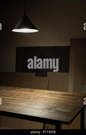Lamp hanging over empty wooden table in workshop Stock Photo