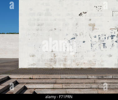 Urban background. Grunge obsolete white street wall and pavement. Stock Photo