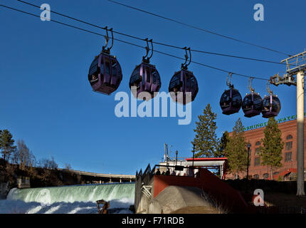 Skyride gondolas cross Spokane River directly below the waterfall then pass under Monroe Bridge from Huntington Park; Spokane. Stock Photo