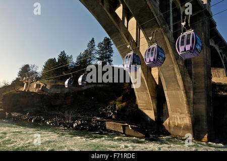 Skyride gondolas cross Spokane River directly below the waterfall then pass under Monroe Bridge from Huntington Park; Spokane. Stock Photo