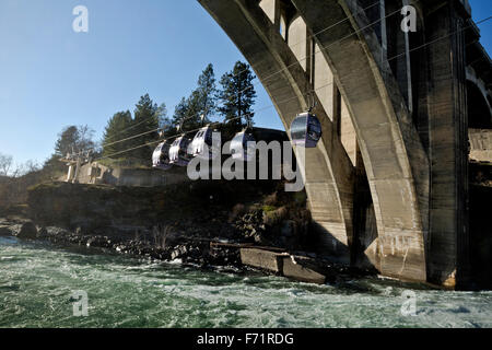 Skyride gondolas cross Spokane River directly below the waterfall then pass under Monroe Bridge from Huntington Park; Spokane. Stock Photo