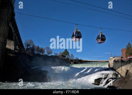 Skyride gondolas cross Spokane River directly below the waterfall then pass under Monroe Bridge from Huntington Park; Spokane. Stock Photo