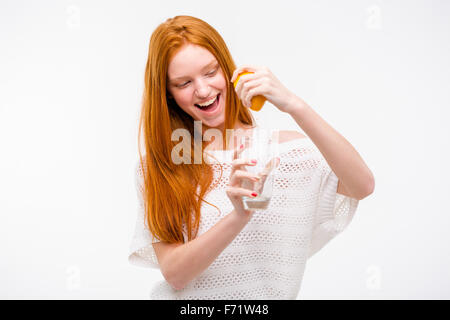 Excited smiling happy pretty young woman squeezing orange juice from the orange into a glass by hand Stock Photo