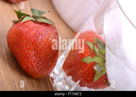 Strawberry on wooden plate and strawberry frozen with ice in cup Stock Photo