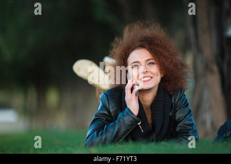 Portrait of a happy woman talking on the phone on green grass outdoors Stock Photo