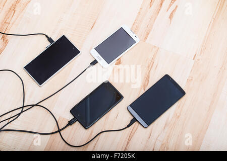 four smartphones connected to chargers Stock Photo