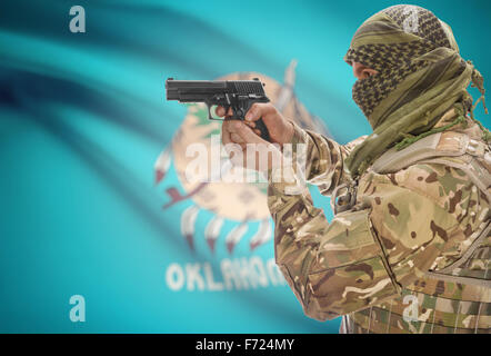 Male in muslim keffiyeh with gun in hand and flag on background series - Oklahoma Stock Photo