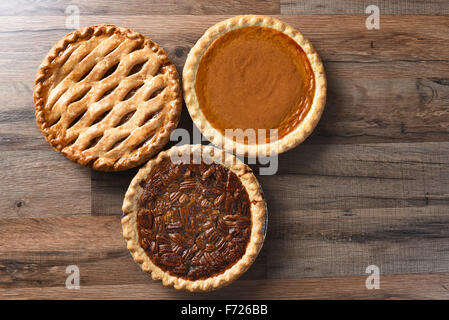 Three pies for Thanksgiving on a wood surface. The desserts include apple, pumpkin and pecan pies - all traditional treats for t Stock Photo