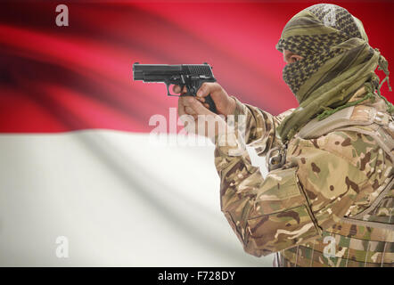 Male in muslim keffiyeh with gun in hand and national flag on background series - Indonesia Stock Photo