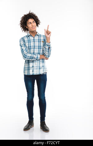 Full length portrait of a happy thoughtful afro american man with curly hair pointing finger up at copyspace isolated on a white Stock Photo
