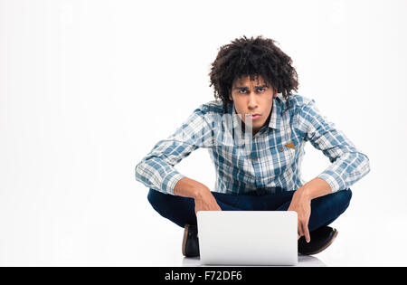 Sad afro american man sitting on the floor with laptop computer and looking at camera isolated on a white background Stock Photo