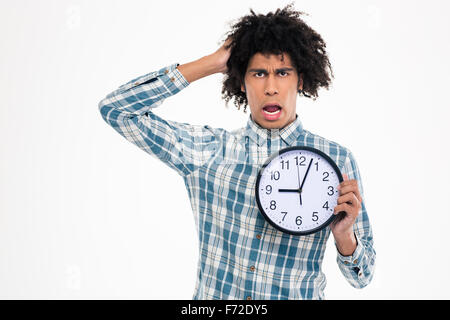 Portrait of a shocked afro american man holding wall clock isolated on a white background Stock Photo