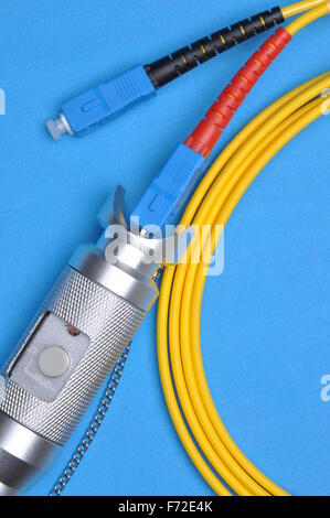Fiber optic tester and optical patch cord on blue background Stock Photo