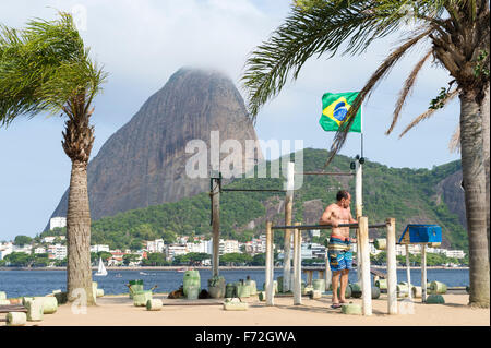 RIO DE JANEIRO, BRAZIL - OCTOBER 17, 2015: Brazilian man exercises at an outdoor workout station in the Flamengo neighborhood.