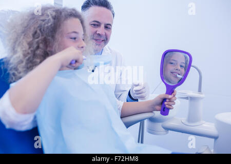 Pediatric dentist teaching girl how to brush teeth Stock Photo