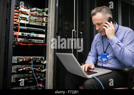Technician using laptop in server room Stock Photo