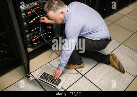 Technician using laptop to analyse server Stock Photo