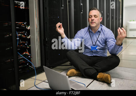 Technician meditating in server room Stock Photo
