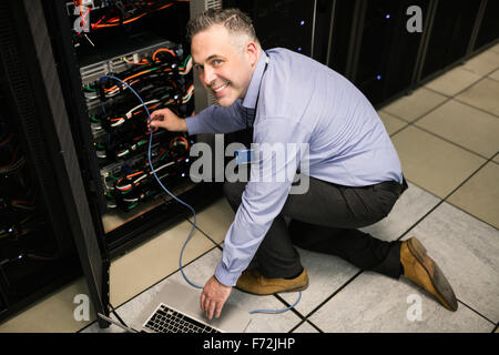 Technician using laptop to analyse server Stock Photo