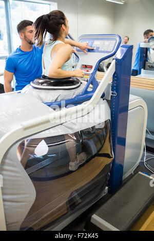 Woman using an anti gravity treadmill beside trainer Stock Photo