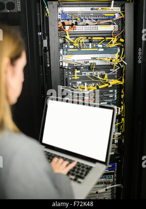 Technician using laptop to analyse server Stock Photo