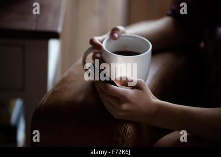 Womans hands holding mug and smartphone Stock Photo
