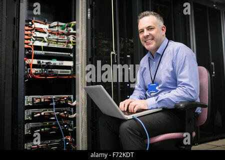 Technician using laptop in server room Stock Photo