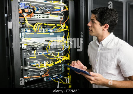 Technician using tablet pc while analysing server Stock Photo