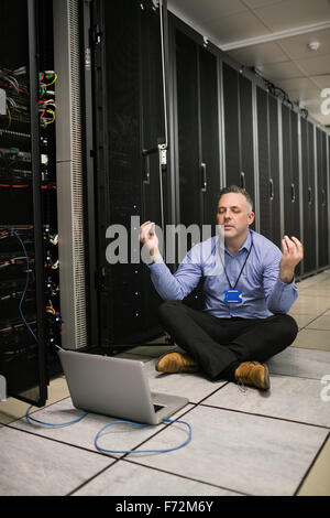 Technician meditating in server room Stock Photo