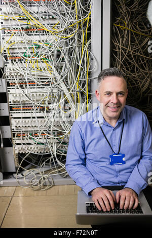 Technician using laptop to analyse server Stock Photo