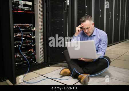 Technician using laptop to analyse server Stock Photo
