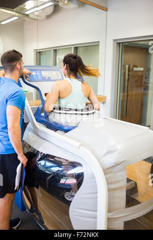 Woman using an anti gravity treadmill beside trainer Stock Photo