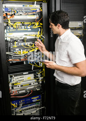 Technician using tablet pc while analysing server Stock Photo