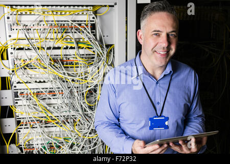 Technician using tablet pc while analysing server Stock Photo